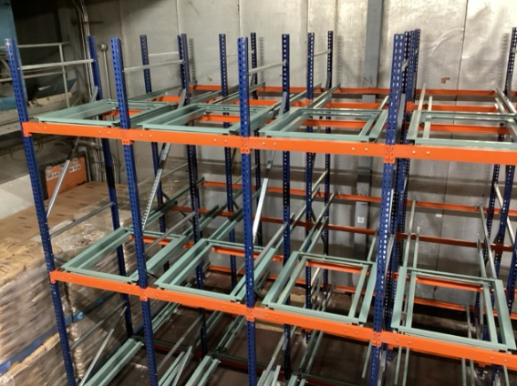 Forklift loading a pallet onto a push back racking cart from the aisle