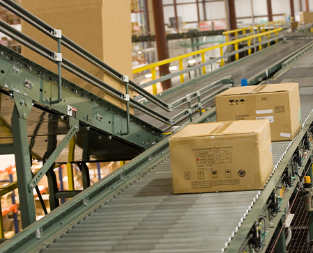 Parcel conveyor moving cartons and packages for order fulfillment